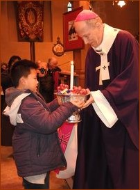 Monseigneur Pierre d'Ornellas reçoit l'offrande d'un enfant laotien, suivi de nombreuses personnes du Laos apportant leurs présents