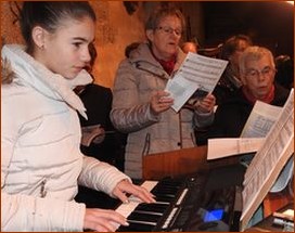Clémence accompagne le chant que sa grand-mère et la chorale interprètent