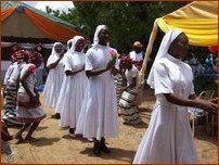 Sr Léa, une fleur dans les mains, s'avance vers l'autel, précédée et suivie des Sœurs professes et accompagnées des fillettes qui dansent Sr Léa, une fleur dans les mains, s'avance vers l'autel, précédée et suivie des Sœurs professes et accompagnées des fillettes qui dansent