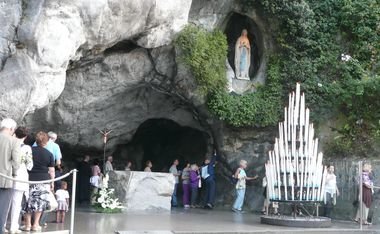 A la grotte de Lourdes, les pèlerins touchent avec foi le rocher de l'Apparition A la grotte de Lourdes, les pèlerins touchent avec foi le rocher de l'Apparition